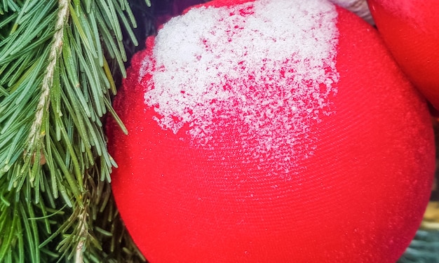 Close-up of a red shiny Christmas ball covered with snow, the concept of a festive decoration and background.