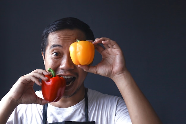 Close up of red and yellow paprika holding by male chef hands