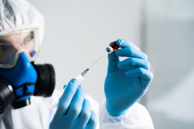 Close-up. researcher holds a syringe and an ampoule with the tested vaccine. photo with a copy-space.