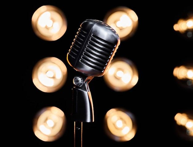 Close up of retro metal microphone placed on dark stage during event in studio with blurred bulb