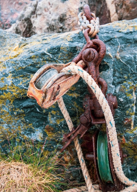 Photo close-up of rusty chain rope and pulley on rock