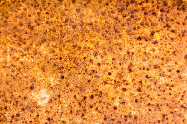 Photo close up of rusty metallic plate with bright yellow color and spots of rust as background