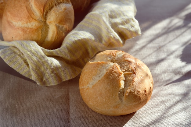 Close-up on rusty round bun, Kaiser or Vienna rolls on table covered with linen tablecloth