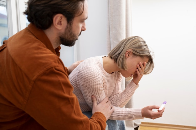 Close up sad couple with pregnancy test