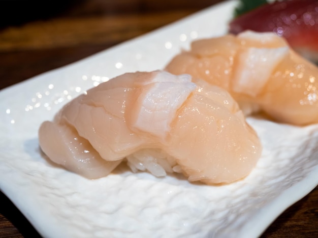 Close up scallop sushi hotate hotategai nigiri sushi made of scallop on top of the japanese rice decoration on small white dish on wood table japanese food cuisine style