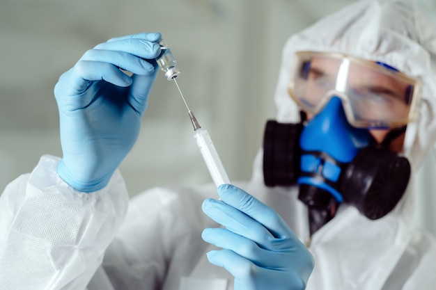 Close-up. scientist microbiologist holds a syringe and an ampoule with the tested vaccine.