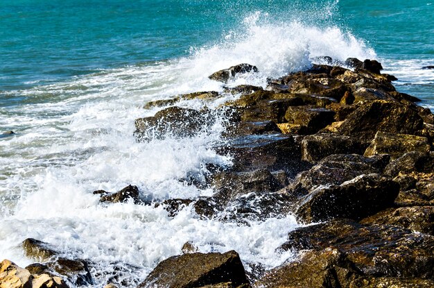 Close-up of sea waves breaking on the rocks of Vilanova y la Geltru beach.