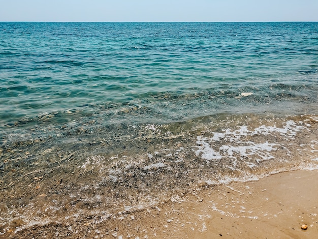 close up sea waves stones shells beach summer day. top view above transparent water. ocean clear sea