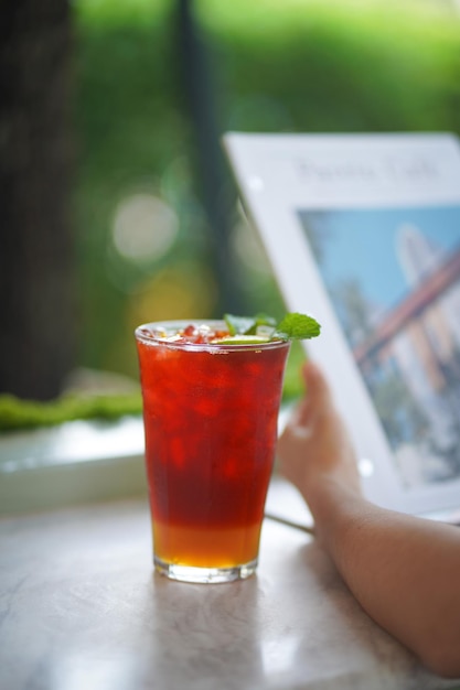 Close up and selective focus glass of ice honey lemon tea white blurred hand holding magazine.