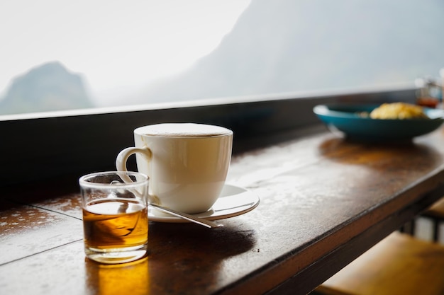 Close up and selective focus white cup of hot coffee on the wooden table at restaurant or cafe .