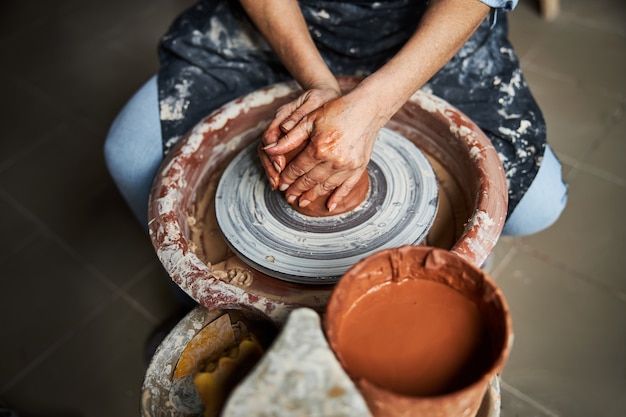 Close up of senior female potter kneading and shaping clay on pottery wheel