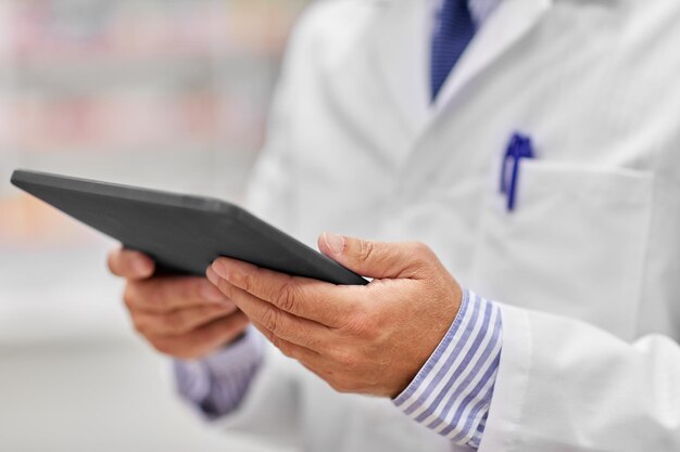 Photo close up of senior pharmacist with tablet pc