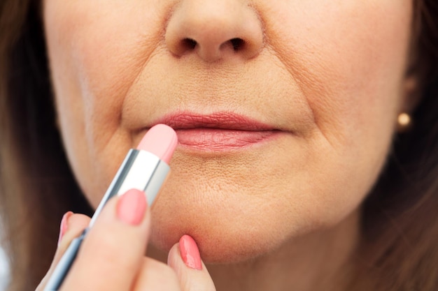 close up of senior woman applying lipstick