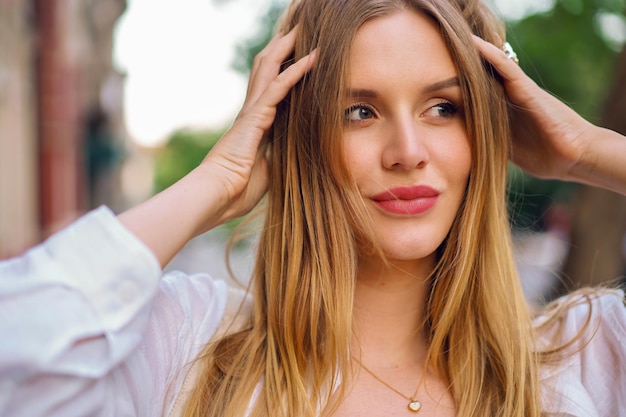 Close up  sensual portrait of elegant blonde woman posinf on the street, spring summer time, natural make up.