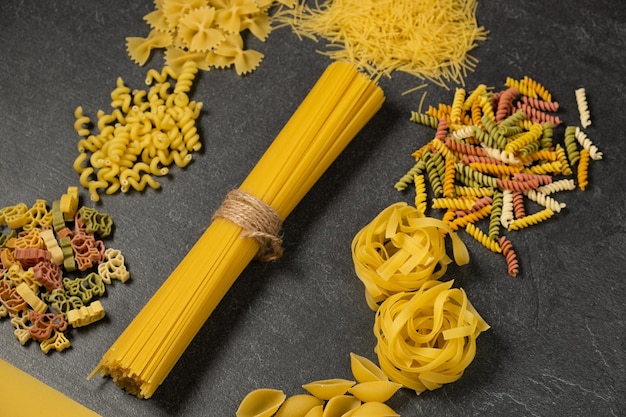 Close up of several types of dry pasta on dark background