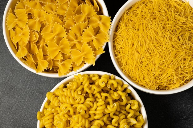 Close up of several types of dry pasta in a plate on dark background