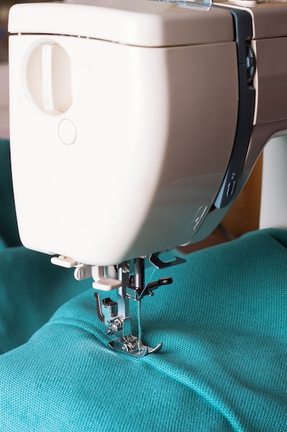 Close up of sewing machine working with turquoise fabric