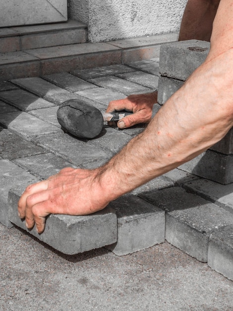 Close up shit of construction worker paving the brick road