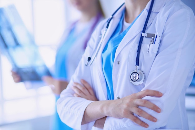 Close up shoot of doctor's crossed hands and colleague with x-ray on the background.