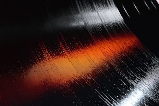 Close-up shot of 12-inch LP vinyl record groove with white and orange lights.