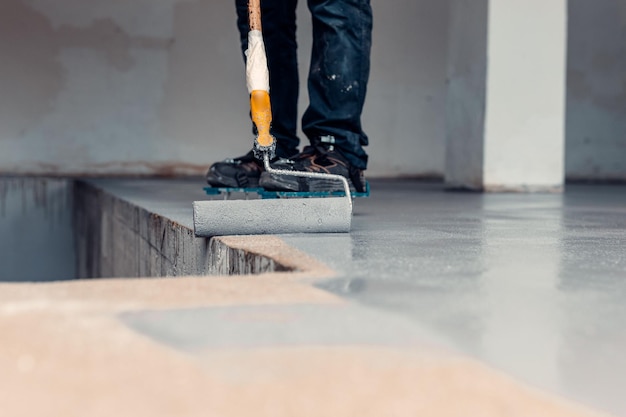 close up shot of a construction worker applying grey epoxy resin in an industrial hall