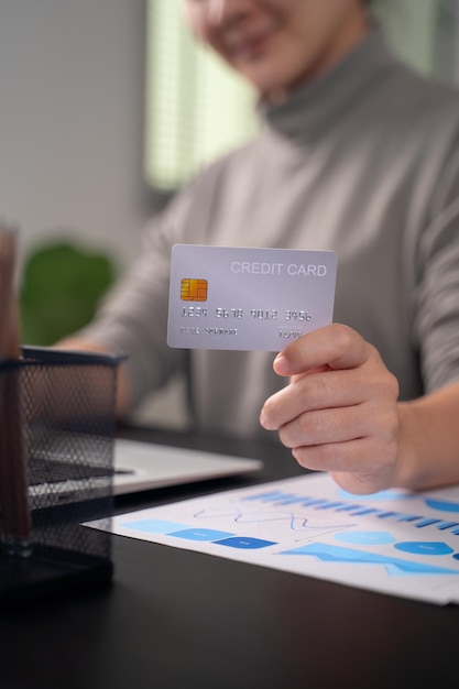 Close up shot of females hands holding credit card typing message on laptop for shopping online at home office