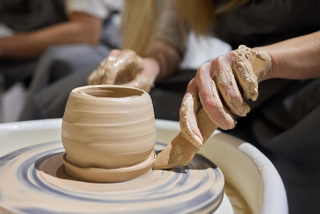 Close up shot of hands of crafts people working with clay in pottery studio