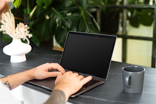 Close up shot of a man sitting at the table and working on laptop at home