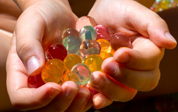 Close-up shot of multiple colored balls (orbis) in the small hands of a child.