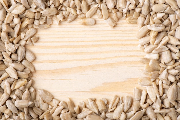 Close up shot of peeled sunflower grian on wooden background natural frame