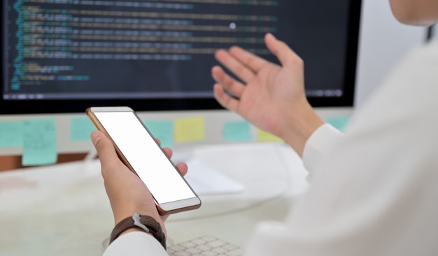 Close-up shot of Programmer hand using blank screen smartphone.