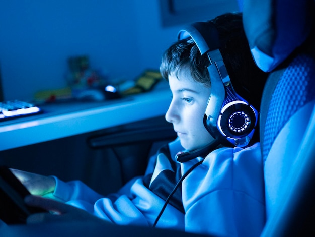 Close up shot of teenager kid playing video game at neon light background concept of entertainment hobbies and technology