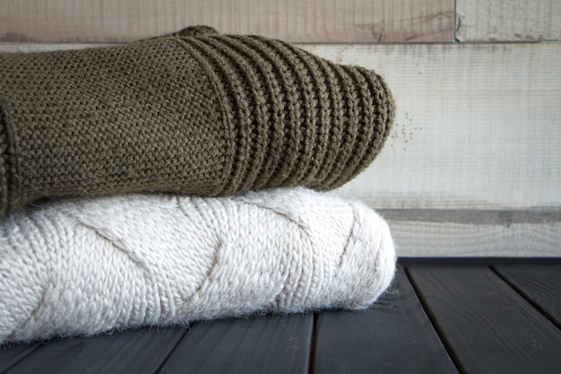 Close-up shot of two knitted from natural wool sweaters, on a black wooden table