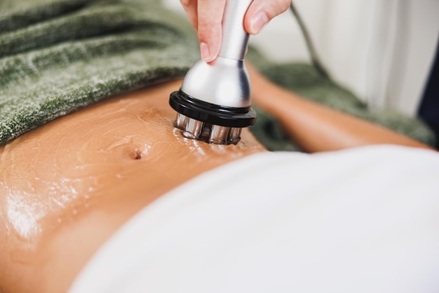 Close-up shot of a unrecognizable woman getting a RF lifting treatment on abdomen at the beauty salon.