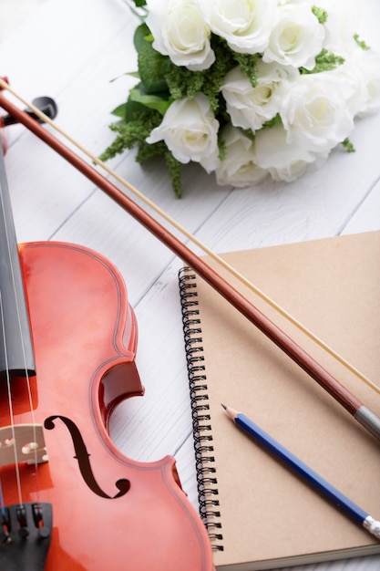 Close-up shot violin orchestra instrumental and notebook over white wooden select focus shallow depth of field