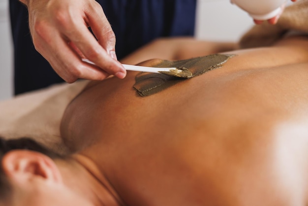 Close-up shot of a woman getting a massage with seaweed mud at the beauty salon.