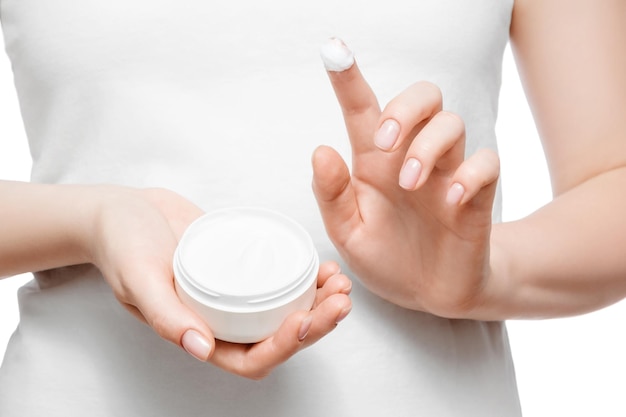 Close up shot of a woman in white tshirt holding a jar of hand cream isolated on white Short natural nails