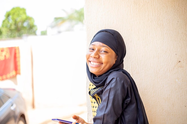 Close up shot of a young smiling Nigerian woman holding her cell phone