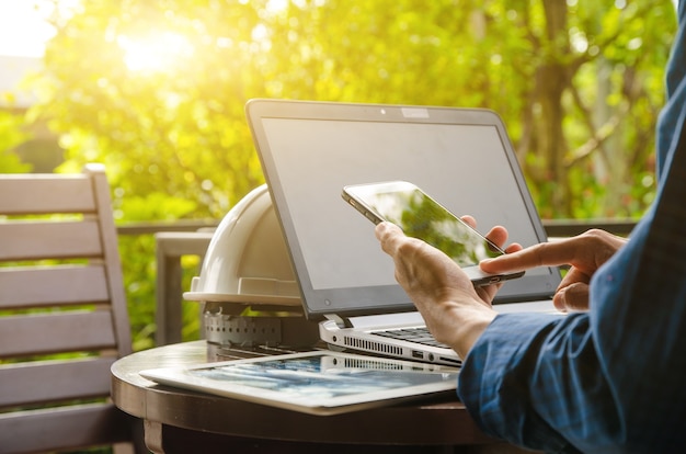 Close-up shots of engineers working with laptop computers sitting on a wooden table with a natural background.