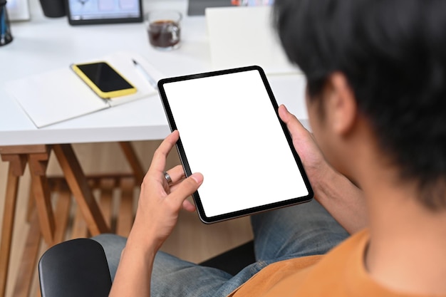 Close up over shoulder view of businessman sitting on chair and using digital tablet