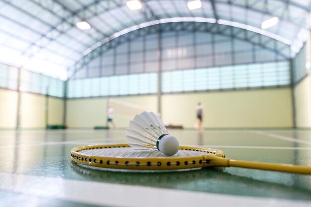 Close up shuttlecock on badminton racket at courts with players competing