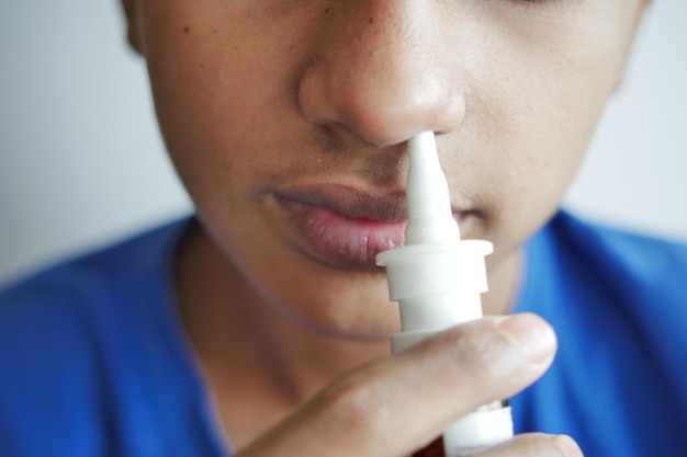 Close up of sick boy using nasal medicine spray