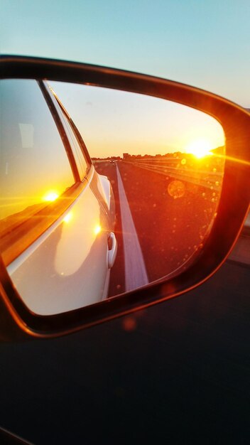 Photo close-up of side-view mirror during sunset