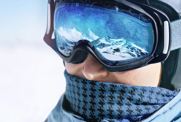 Close up of the ski goggles of a man with the reflection of snowed mountains