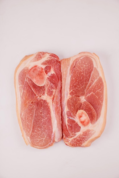 Close up of sliced raw pork shoulder with skin on dark surface.