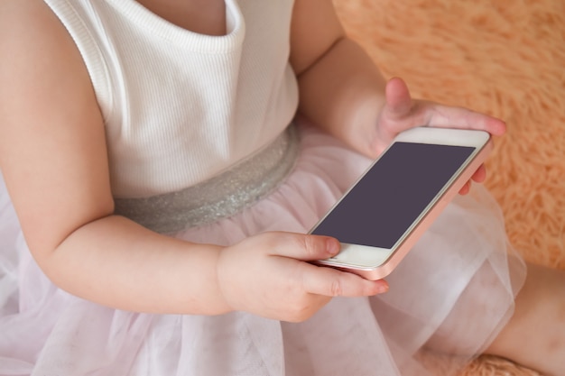 Photo close-up of a small child's hands holding the phone in their hands