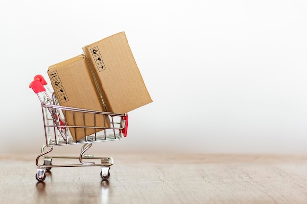 Photo close-up of small shopping cart with cardboard boxes on table