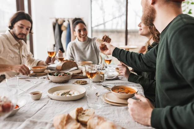 Close up smiling african american woman sitting at the table happily taking slice of bread from friend