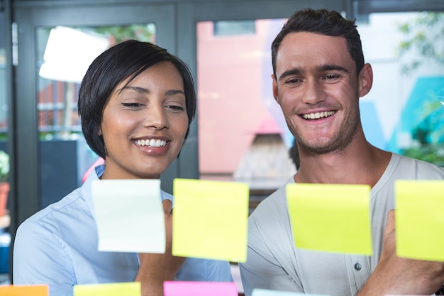 Close up of smiling colleagues looking at sticky notes