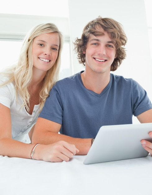 Close up smiling couple holding a tablet and looking at the camera